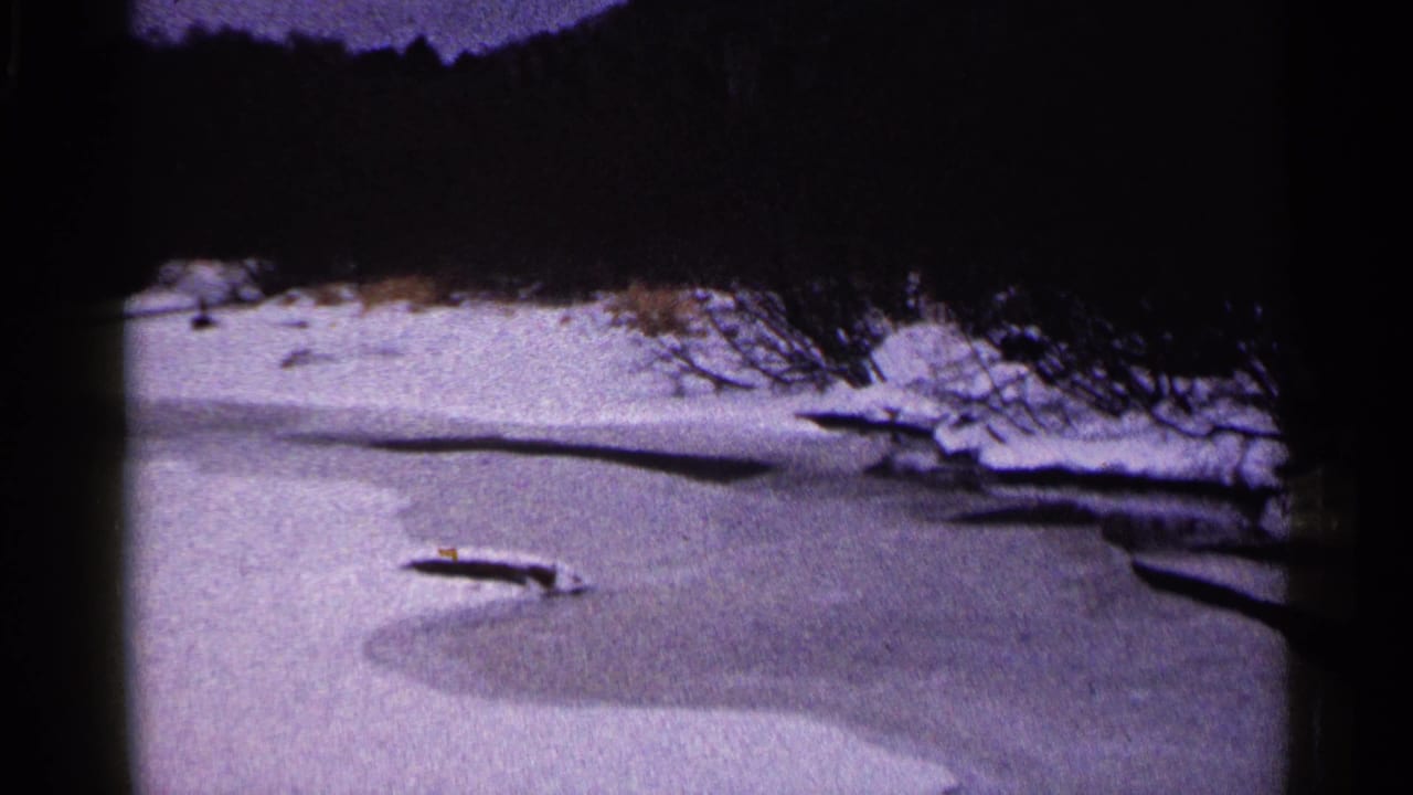 Frozen river with a snow-covered shoreline and dark shadowed area above.
