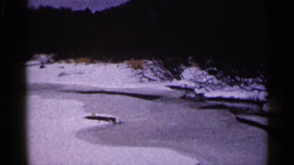 Snowy Duluth riverbank and frozen water seen in soft, purple-tinged 8mm home-movie footage.
