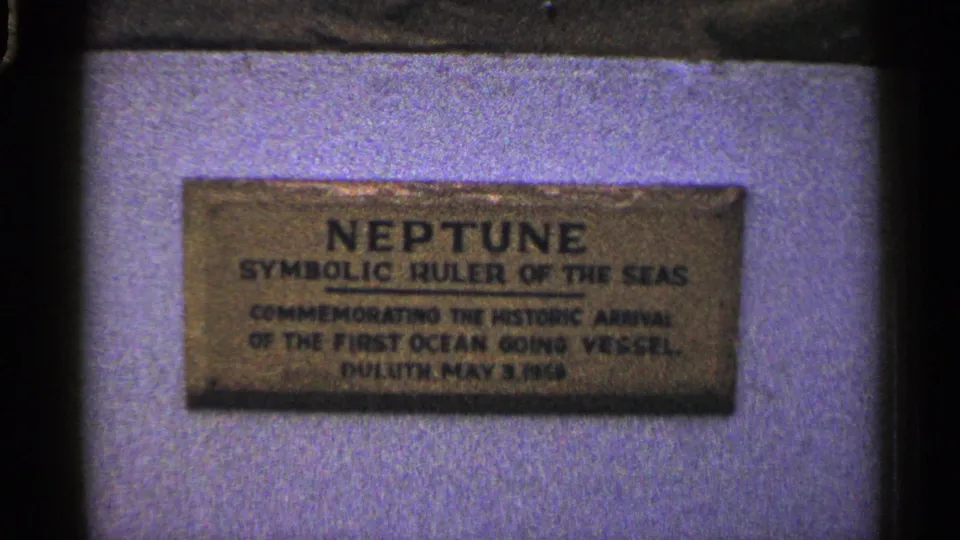 Duluth close-up of the Neptune plaque commemorating the first ocean-going vessel arrival, filmed on grainy 8mm.
