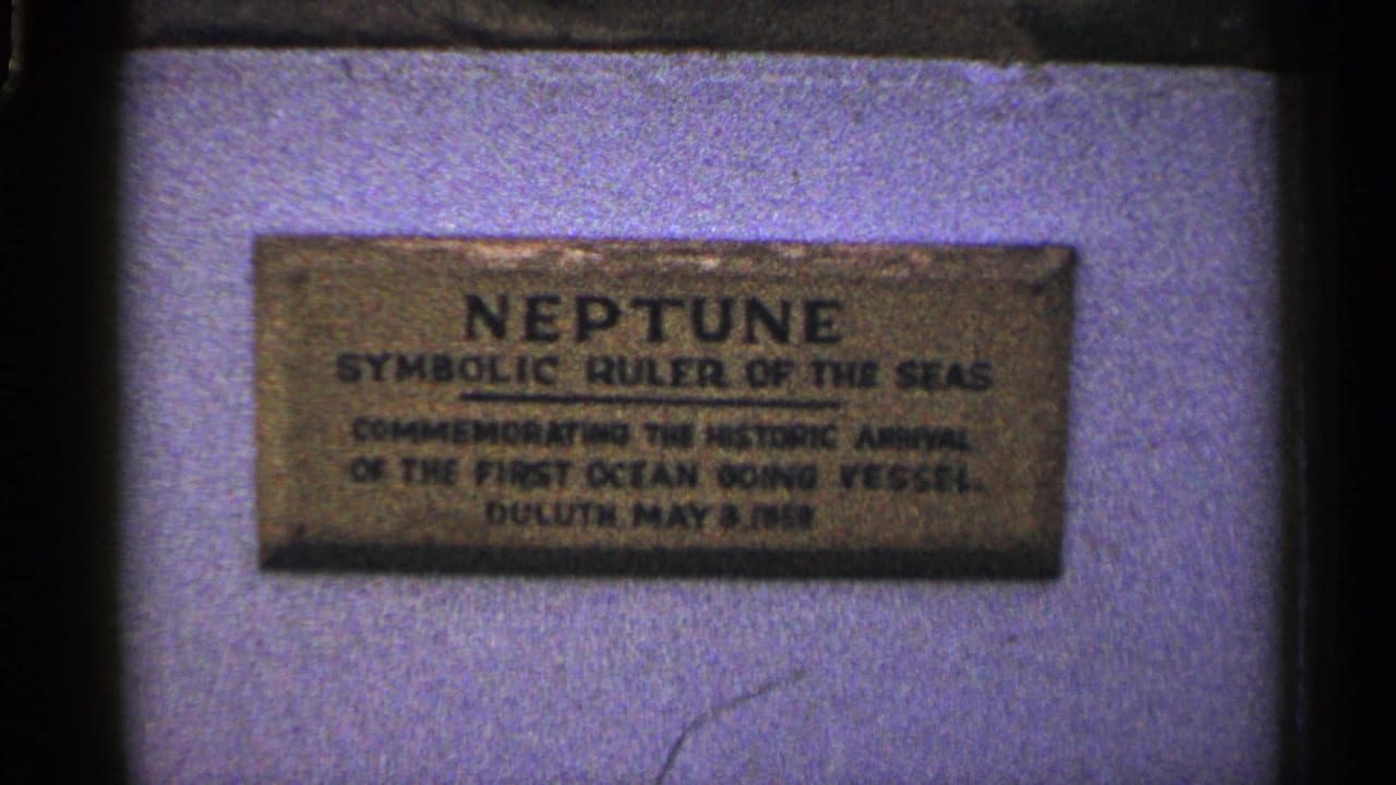Close view of a Neptune commemorative plaque mounted on a pale surface.