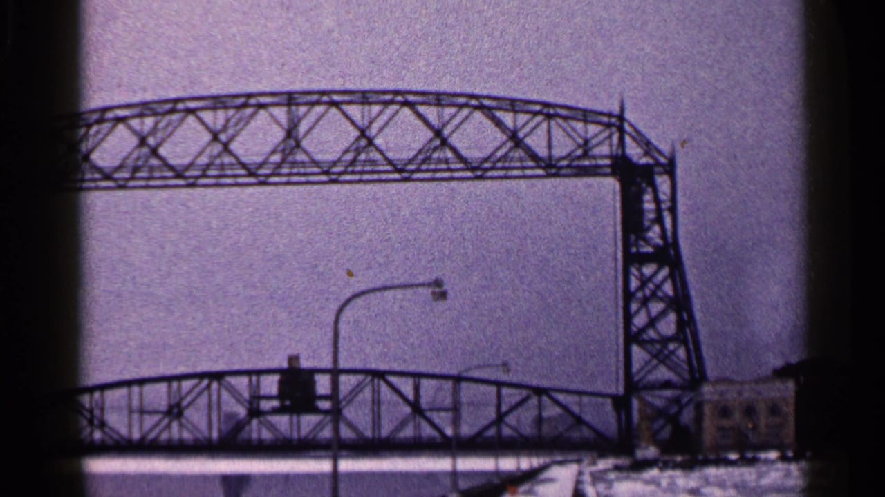 Lift bridge tower and truss above a lower bridge, with snow and buildings at right.