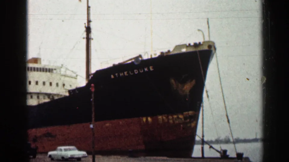 1960 Duluth harbor frame with the bow of the docked vessel ATHELDUKE and a small white car below.