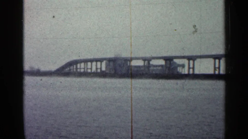 Duluth-area waterfront view from 1960 showing a long bridge span over open water through a soft 8mm frame.