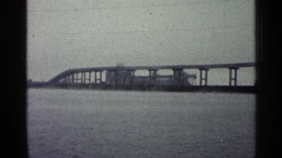 A long bridge over open water appears in the 1960 Duluth waterfront footage, framed by visible 8mm gate edges.