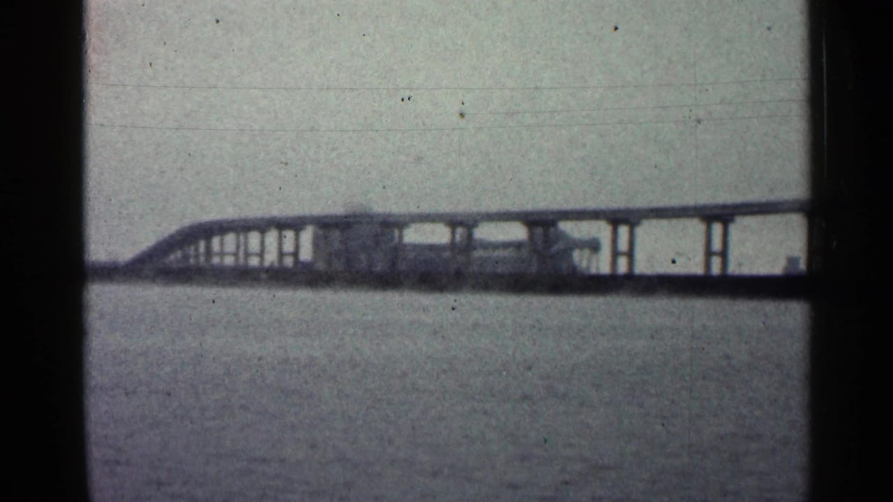 Long elevated bridge crossing water under a pale sky.