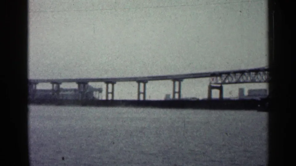 Distant view of the Duluth bridge over water, with darker shoreline structures near the right edge.