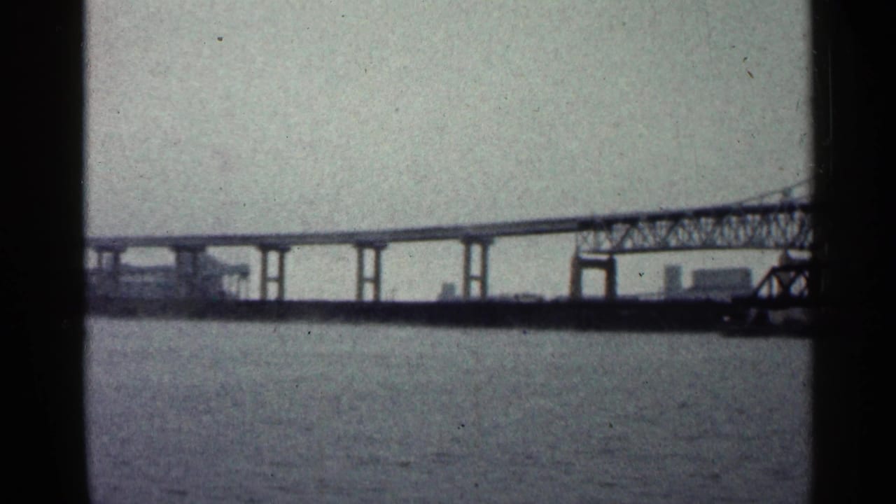 Steel bridge span crossing a wide river under a pale sky.