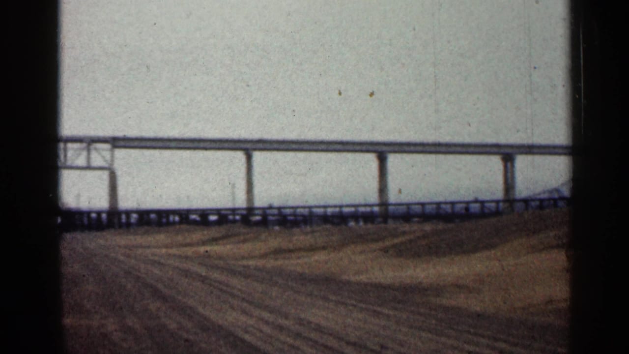 1960 Duluth frame with the bridge continuing across the background, its roadway supports visible above the riverbank.