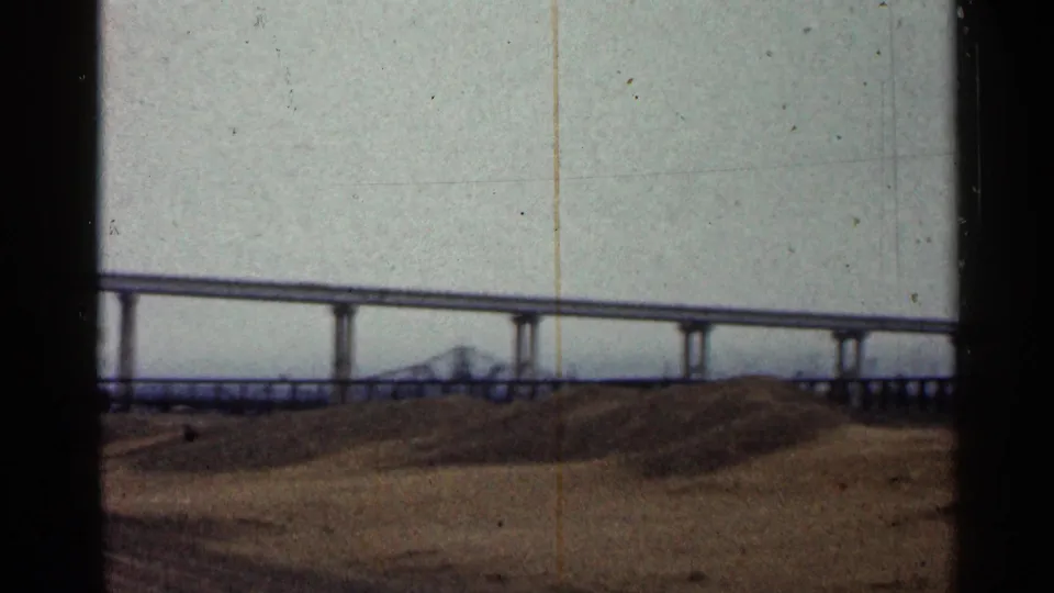 1960 Duluth home-movie view of a long bridge span with a smaller truss form visible in the distance over the waterfront.