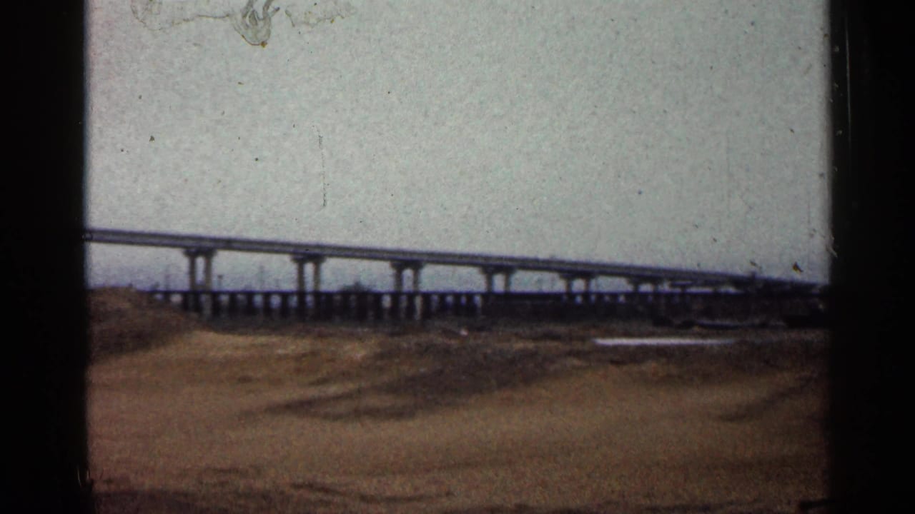 Home-movie view from Duluth in 1960 showing bridge piers, an overpass, and rough open ground below.