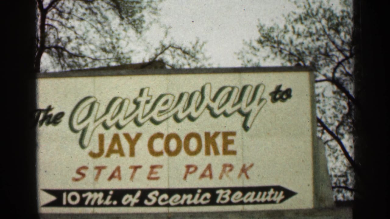 Close 1960 home-movie view of the Jay Cooke State Park gateway sign, showing faded colors, script lettering, and arrow text.