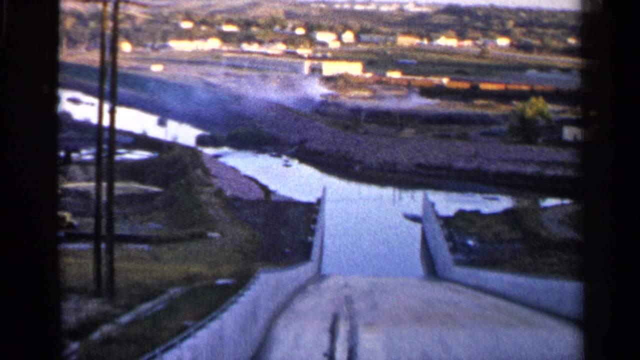 River and concrete channel seen from above with industrial buildings across the water.