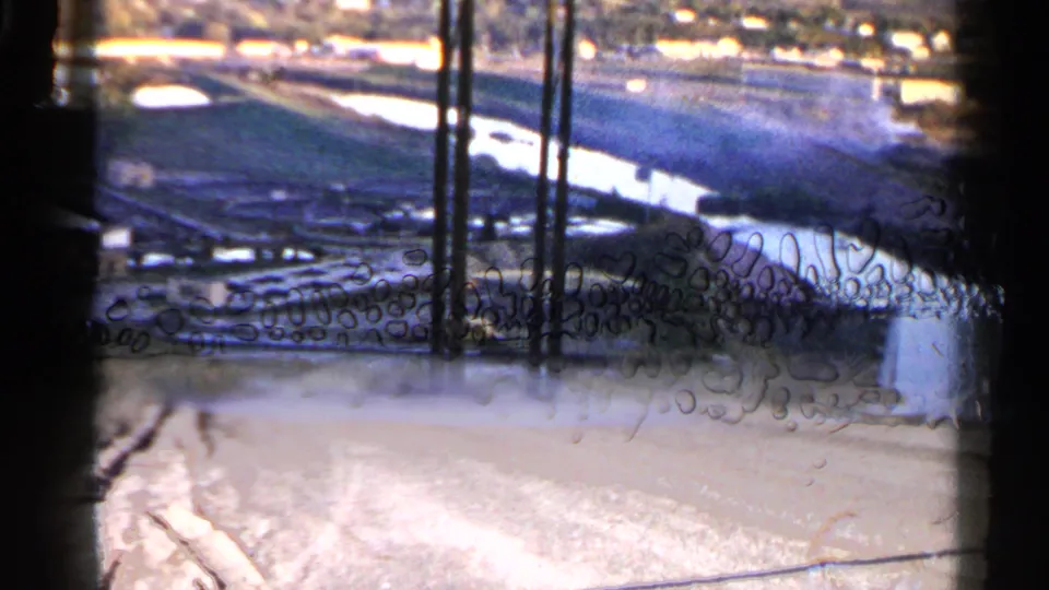 The 8mm frame shows the Sioux Falls channel scene partly obscured by film edges, scratches, and processing or contact-sheet artifacts.