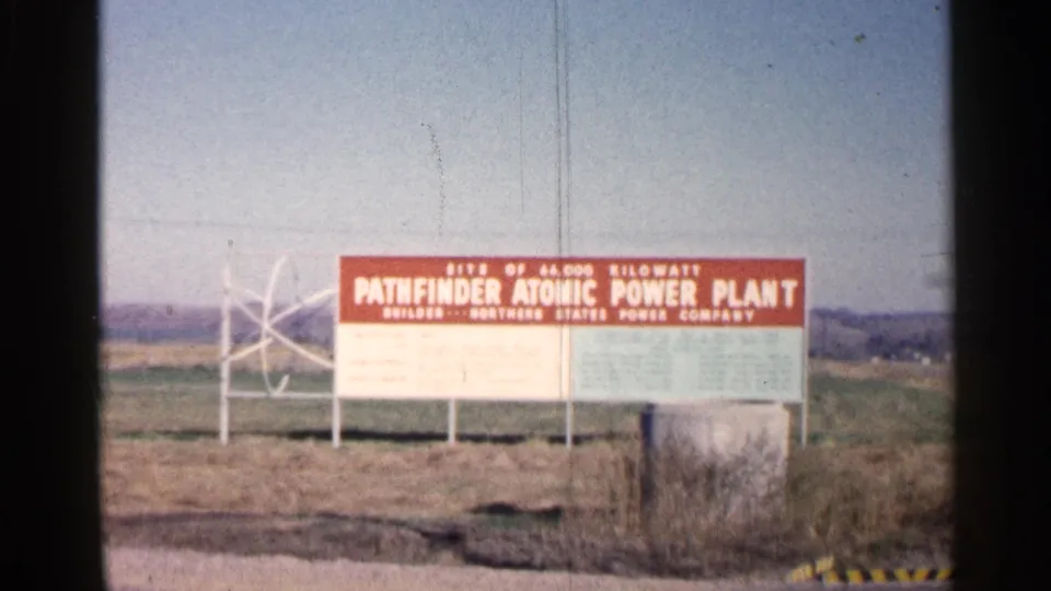 1960 Sioux Falls footage showing a red sign for the Pathfinder Atomic Power Plant in a rural roadside setting.