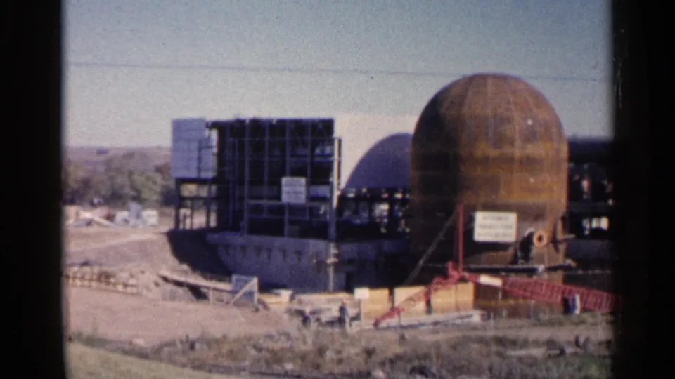 The construction view continues with a large rust-colored dome, scaffolded framework, signage, and open ground in Sioux Falls.