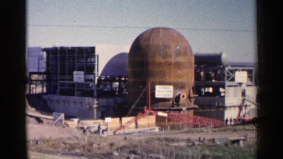 End frame of the 1960 Sioux Falls construction clip, showing the spherical facility structure, framing, signage, and workers at ground level.