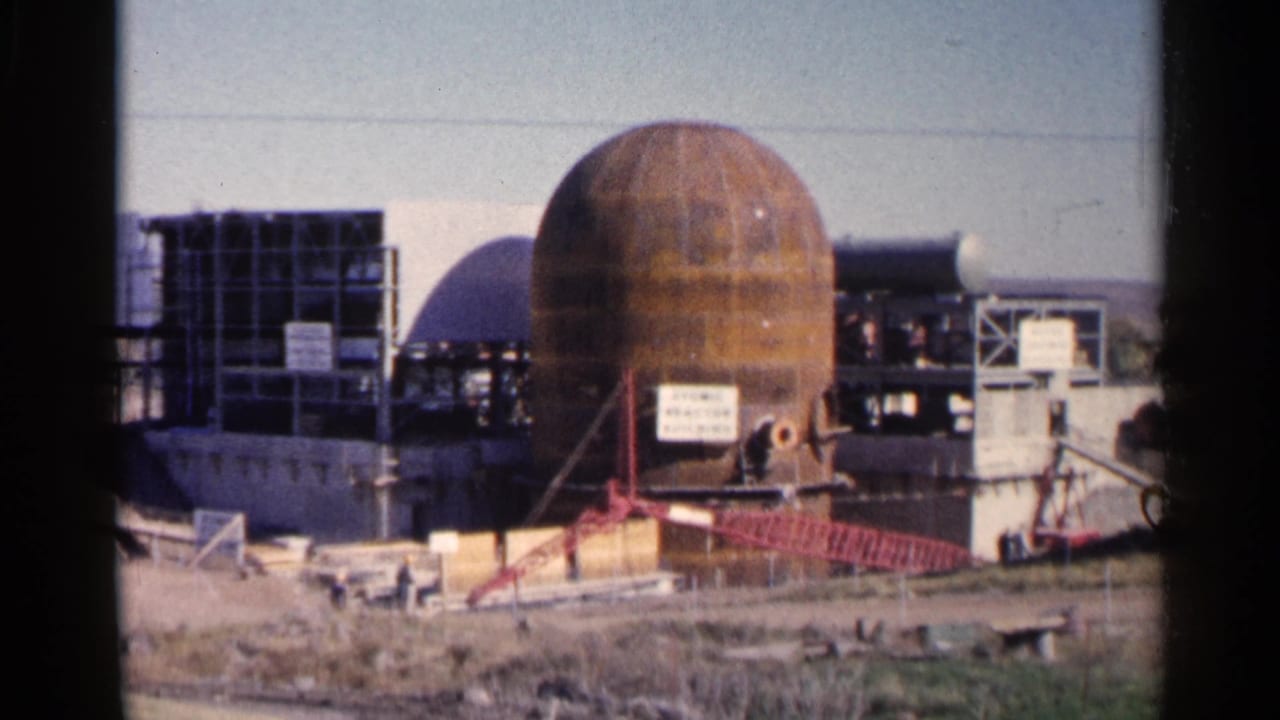 Rust-colored industrial dome under construction with scaffolding and a red crane arm.