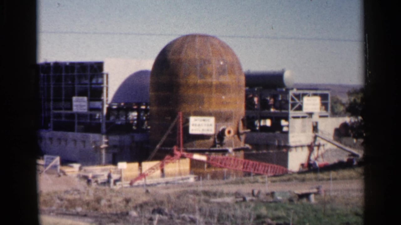 Industrial construction site with large rusted dome, framework, and crane boom.