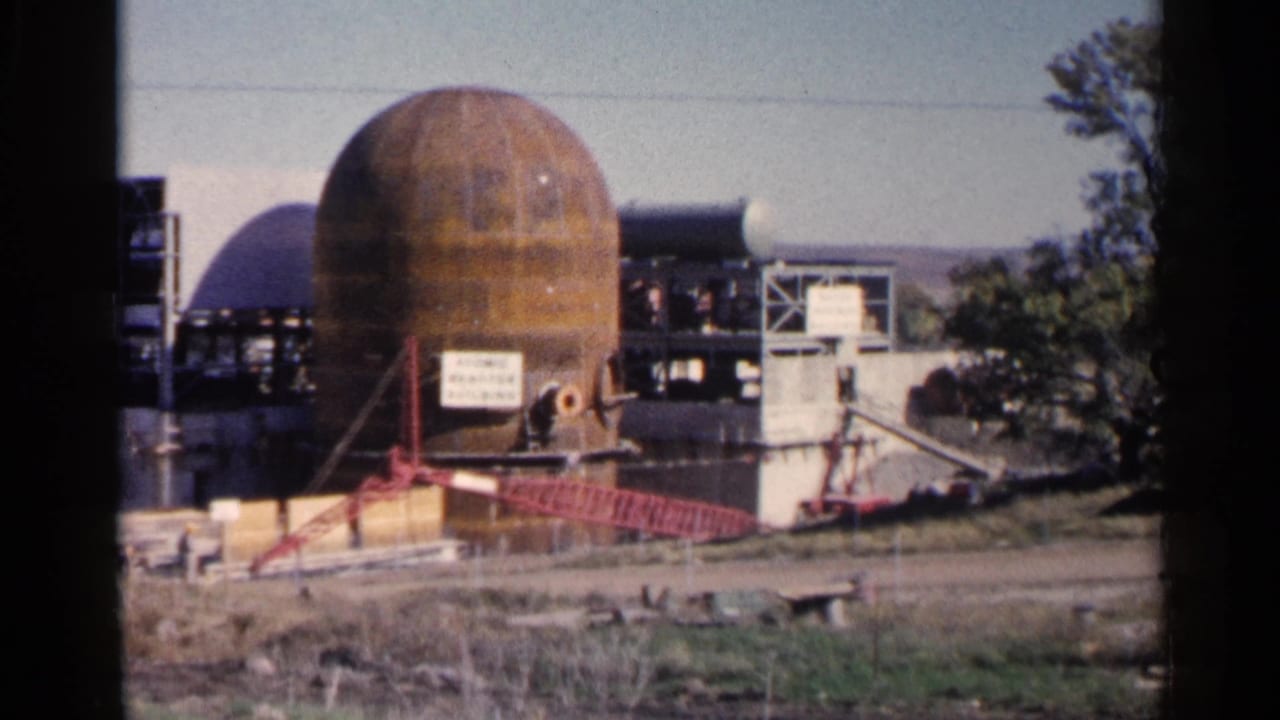 Rusted dome-shaped industrial structure with scaffolding and fencing in open land.