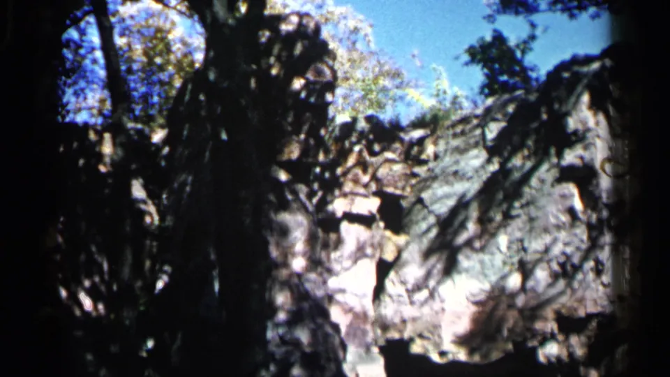 The home-movie frame holds on a pale grey rock formation surrounded by trees in Sioux Falls, South Dakota.