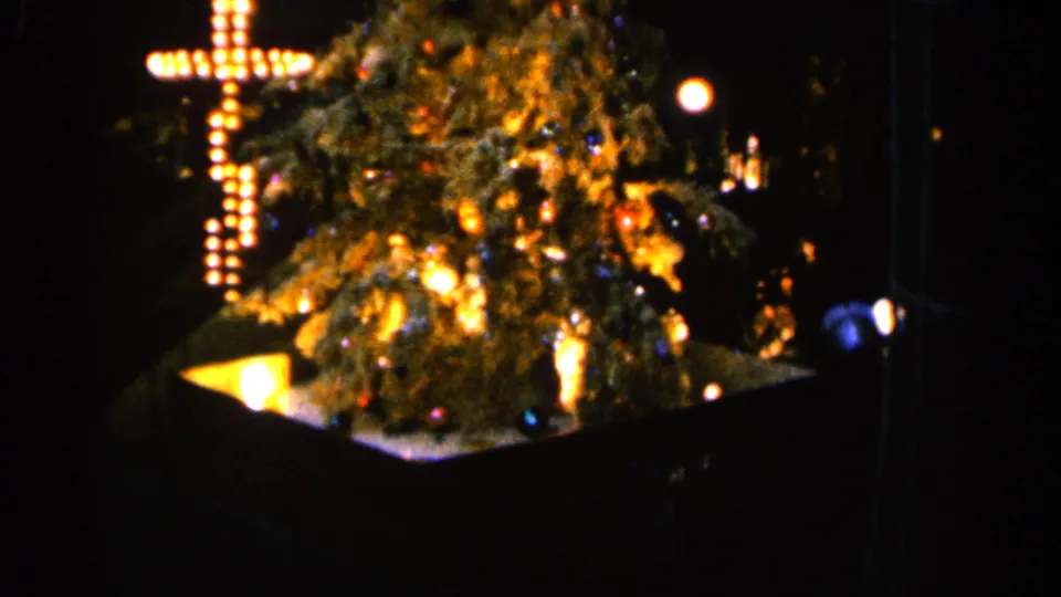 A warmly lit Christmas tree and cross-shaped bulb display appear in the 1960 Sioux Falls holiday home-movie footage.