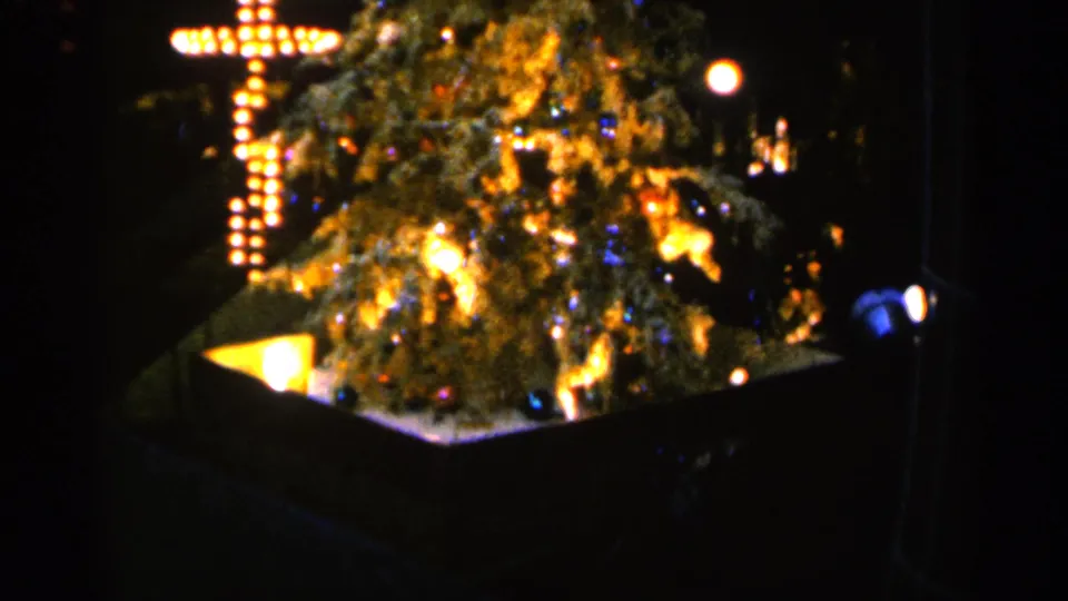 1960 Sioux Falls frame with saturated 8mm color, showing the Christmas tree and illuminated cross in a nighttime display.
