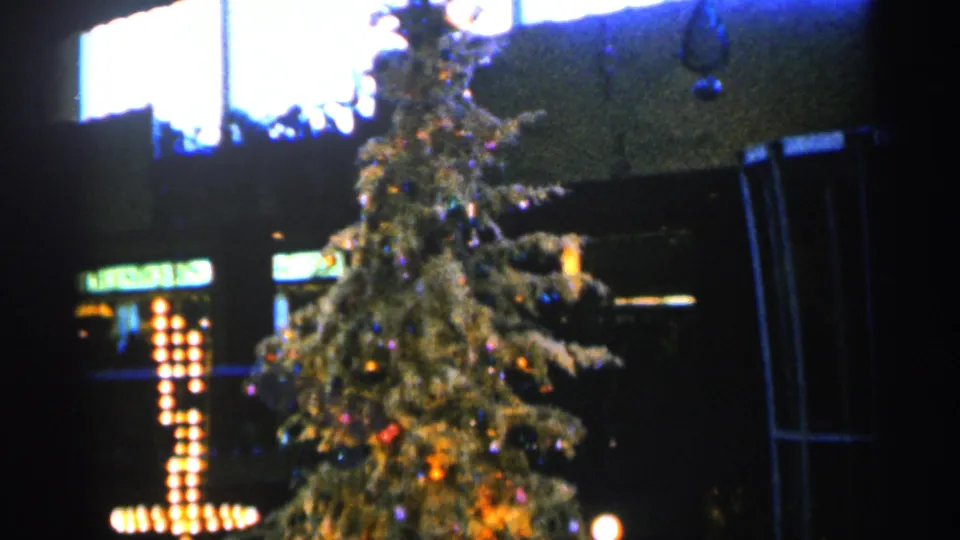 1960 Sioux Falls 8mm frame with the Christmas tree framed to the right and a bulb-lit cross glowing behind it.