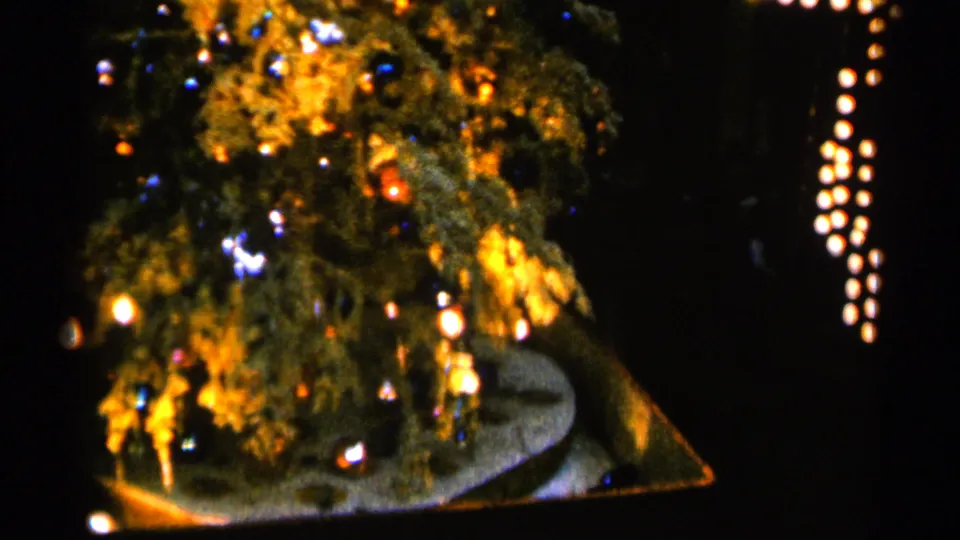 Decorated Christmas tree with colored ornaments and warm lights, likely rotating on a platform in a dim Sioux Falls interior.