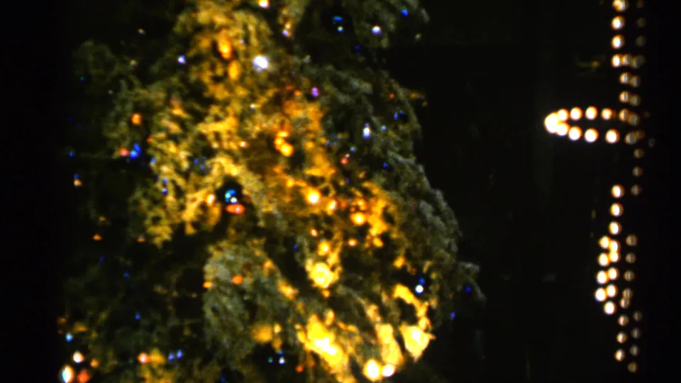 1960 Sioux Falls frame of the Christmas tree later in its rotation, with glowing bulbs and ornaments beside vertical lights.
