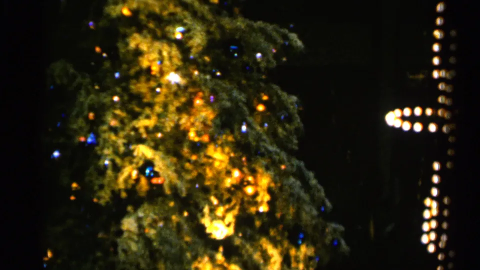 1960 Sioux Falls holiday frame with the revolving tree shifted in view, showing glowing branches and a nearby cross-like light pattern.