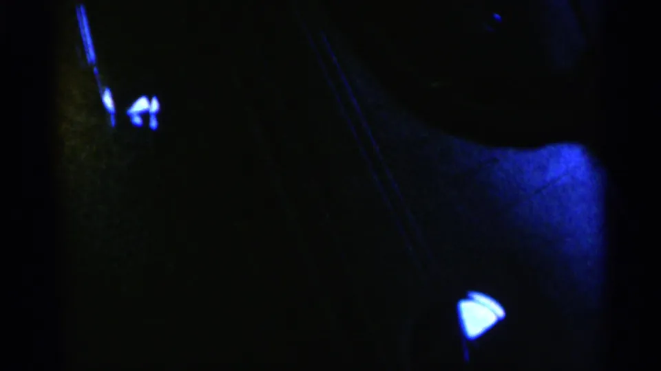Dark 8mm frame with deep blue exposure, scattered reflections, and an indistinct rounded form, likely recorded in very low light.