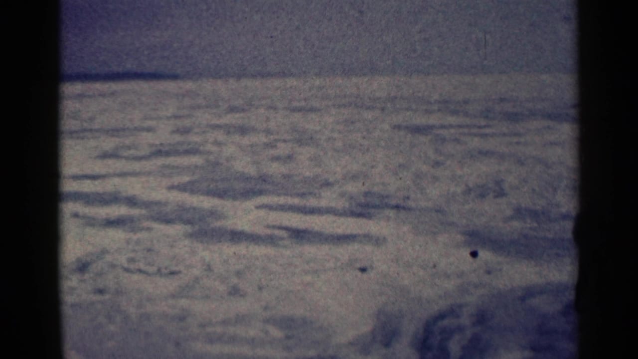 Snow-covered terrain under a muted sky with dark 8mm frame borders.
