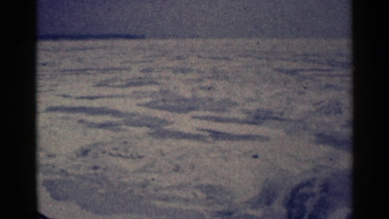 Wide snowy ground with shallow ridges and a dark vertical film border.