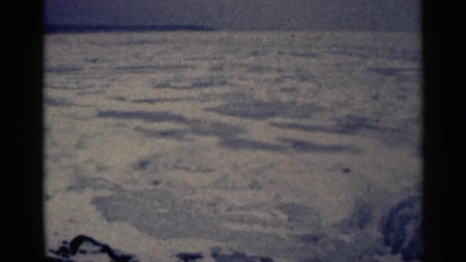 1961 Duluth home-movie still showing uneven snow-covered ground, low hills, and a quiet winter horizon.