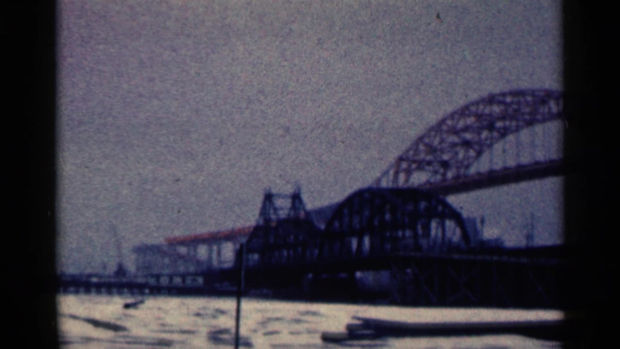 Large arched steel truss bridge over gray water under an overcast sky.