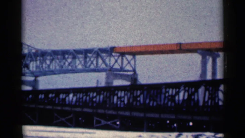 1961 Duluth frame showing the pale steel bridge and orange-toned span above a darker foreground truss bridge near the water.