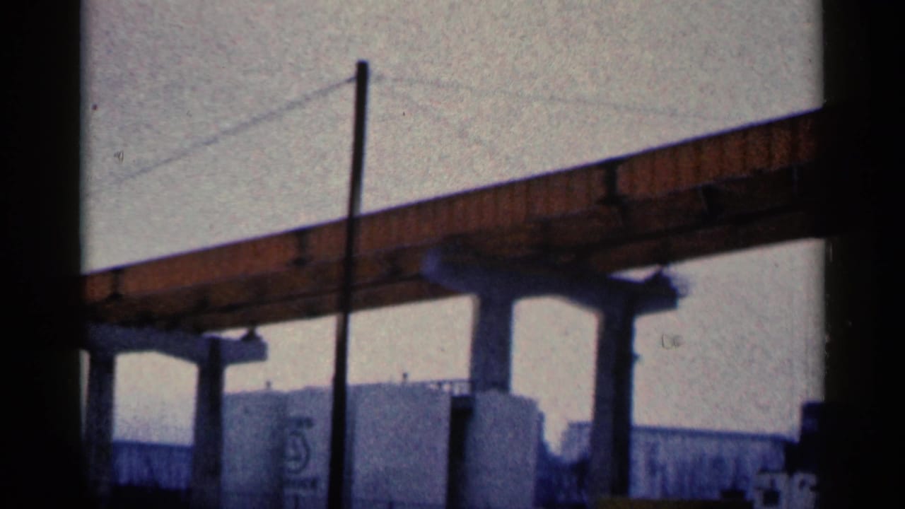 Bridge span and concrete supports above tanks and low industrial structures.