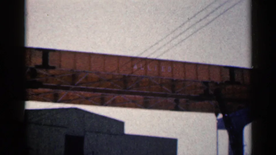 1961 Duluth frame with an overhead railroad span, visible utility lines, support structure, and a dark building roof below.