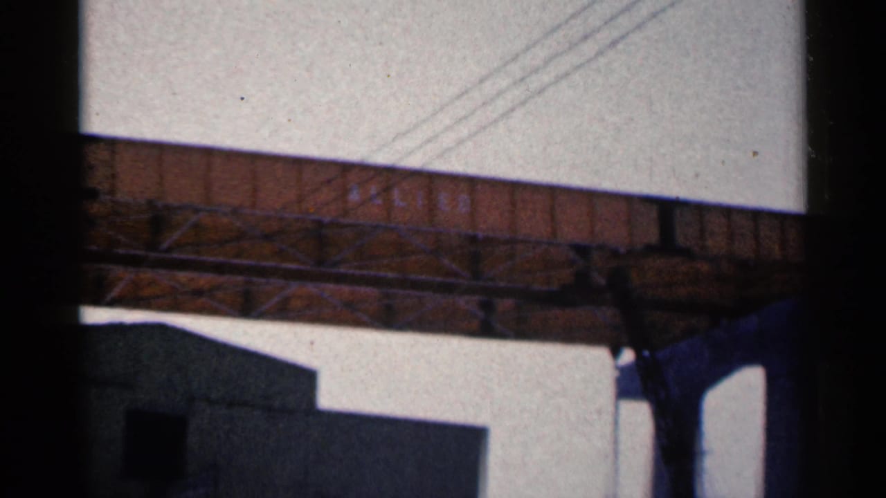 Brown elevated bridge structure with power lines above and a building edge below.