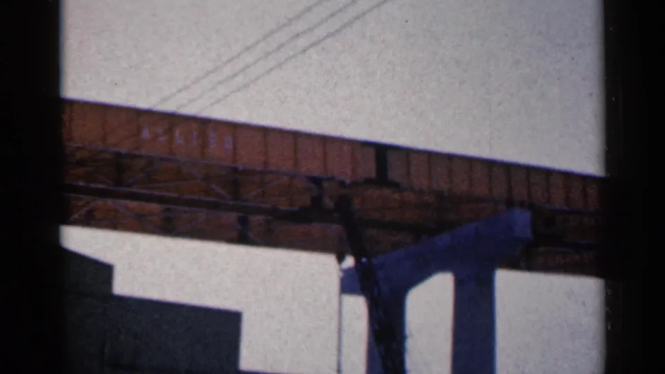 1961 Duluth frame with the elevated metal bridge crossing the view, dark support columns below, and power lines cutting across the overcast sky.