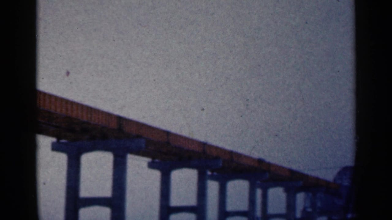 1961 Duluth home-movie frame showing an elevated bridge span on concrete supports beneath a gray sky.
