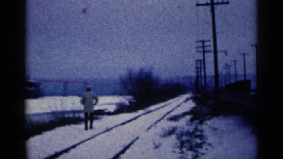 A man walks away along snow-covered rail tracks in Duluth, Minnesota, with utility poles lining the winter scene.