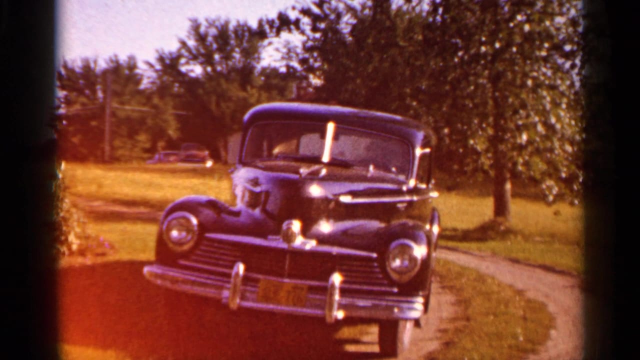 Black sedan seen from the front with warm color shift across the frame.