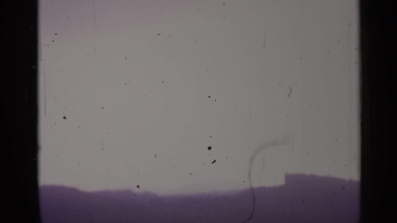 Pale sky over a dark distant ridge or skyline, with film dust visible.