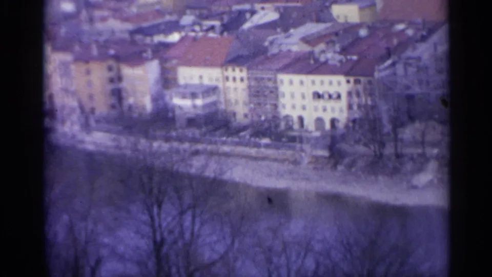 End frame of the 1961 Spain clip showing a purple-tinted 8mm view of the river town, bridge area, bare trees, and red roofs.