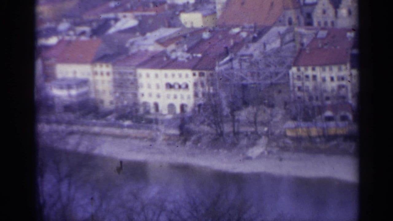 Riverside buildings and rooftops seen through soft purple-tinted 8mm footage.