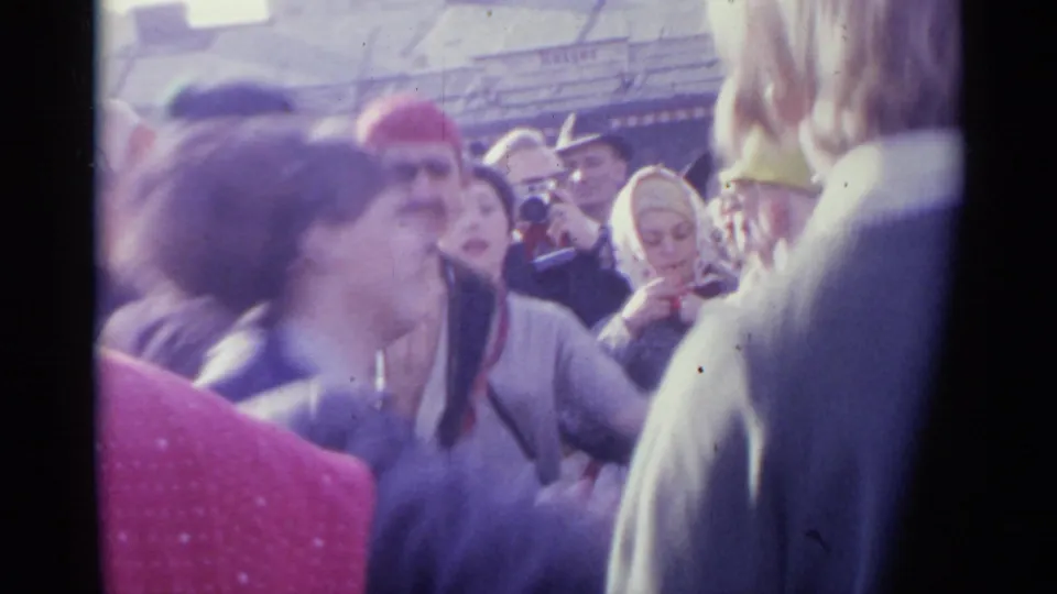 Spain 1961 frame showing people moving together in a stadium crowd, including hats, headscarves, and a red polka-dot foreground garment.