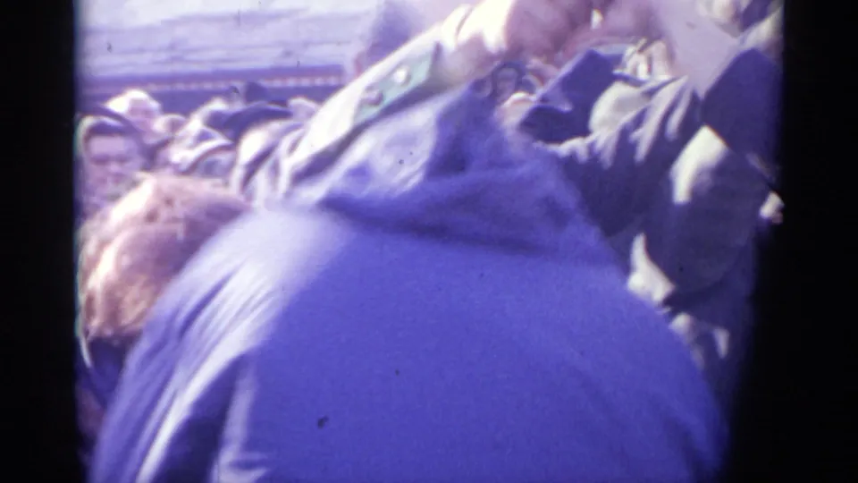 1961 Spain 8mm frame showing raised arms and close-packed adults as participants appear to pass beneath linked hands in a circular dance.