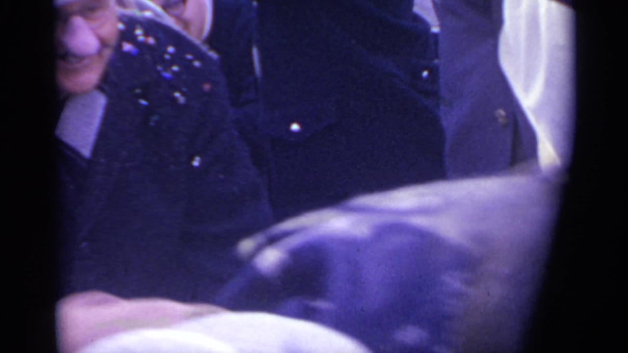 Close handheld view of smiling spectators near parade activity.