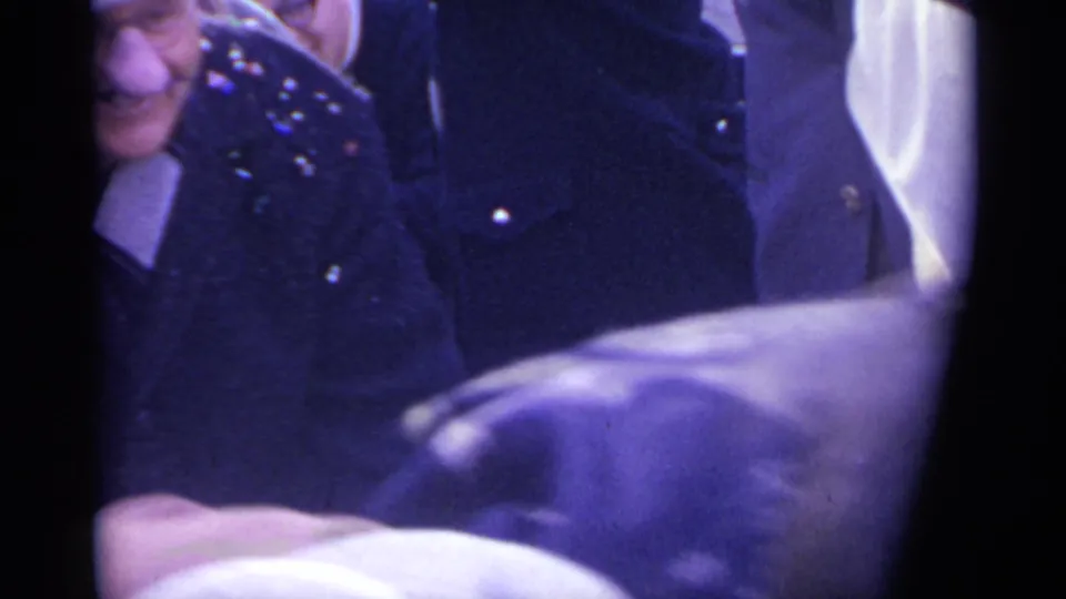 1961 Spain home-movie frame showing spectators close to the camera during a crowded street celebration.
